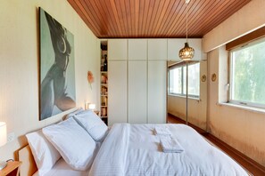 Ein Schlafzimmer mit einem Bett, einem Bücherregal, einem Gemälde und einem Fenster.