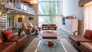 Un vaste espace de vie doté de canapés en cuir, d’une table basse et d’un escalier menant à un niveau supérieur.