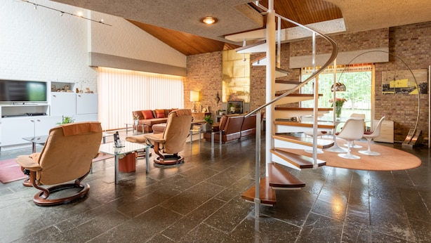 Un vaste espace de vie doté d’un escalier moderne, de meubles en cuir et d’un coin cuisine.