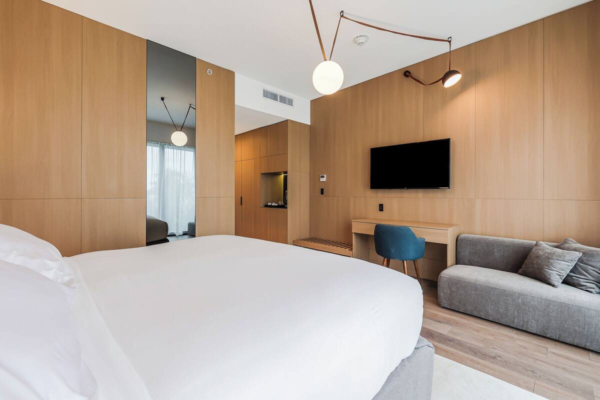 Une chambre d’hôtel moderne dotée d’un grand lit, d’un bureau, d’une télévision à écran plat et d’un canapé.