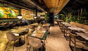 Un restaurante con barra, mesas y vistas al exterior.