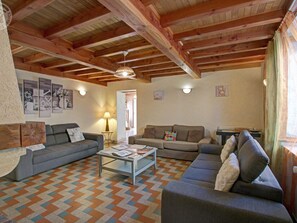 Un salón acogedor con vigas de madera, dos sofás, una mesa de centro y un suelo estampado.