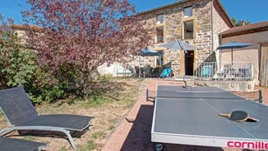 Une cour avec des sièges en plein air, une table de ping-pong et un bâtiment en pierre doté d’un balcon.