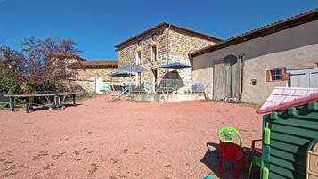 A courtyard with a stone building, outdoor seating, and a play area.