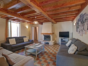 Una sala de estar acogedora con chimenea, sofás, una mesa de centro y un televisor.