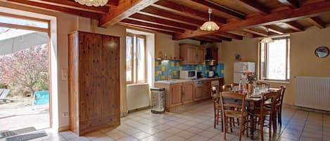 Una cocina amplia con vigas de madera, un comedor con mesa y sillas, y vistas al exterior.