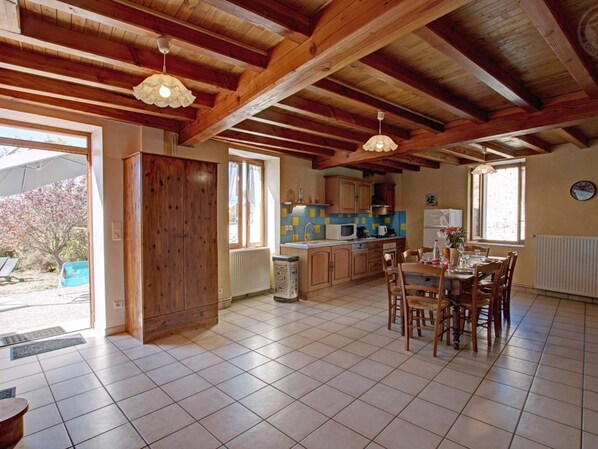 Una cocina amplia con vigas de madera, un comedor con mesa y sillas, y vistas al exterior.