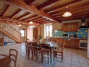 Una cocina rústica con armarios de madera, salpicadero de azulejos y un comedor con mesa y sillas de madera.