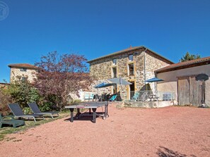 Un patio con mesa de tenis, mobiliario exterior y un edificio de piedra.