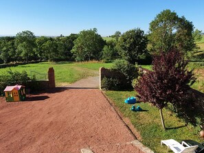 Un chemin de terre menant à une maison avec un mur en briques et une petite maison de jeu.