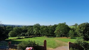 Un paysage rural avec un ciel bleu dégagé, des champs verdoyants et un mur de pierres.
