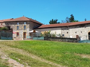 A stone building with a red-tiled roof, a paved pathway, and a grassy area in front. - Charming House with Fireplace and Garden, Pets Welcome (Saint-Paul-de-Vézelin)