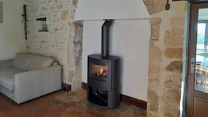 A cozy room with a stone wall, a sofa, and a wood-burning stove. - Authentic Charm in Bonnevent with View and Calm (Marmouillé)