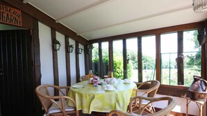 A dining area with wicker chairs and a table set for four, featuring a green tablecloth. - Authentic Charm in Bonnevent with View and Calm (Marmouillé)