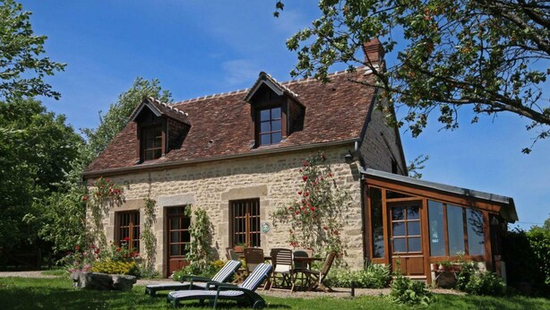 A stone house with a sloped roof, a wooden extension with large windows, and a garden with sun loungers. - Authentic Charm in Bonnevent with View and Calm (Marmouillé)