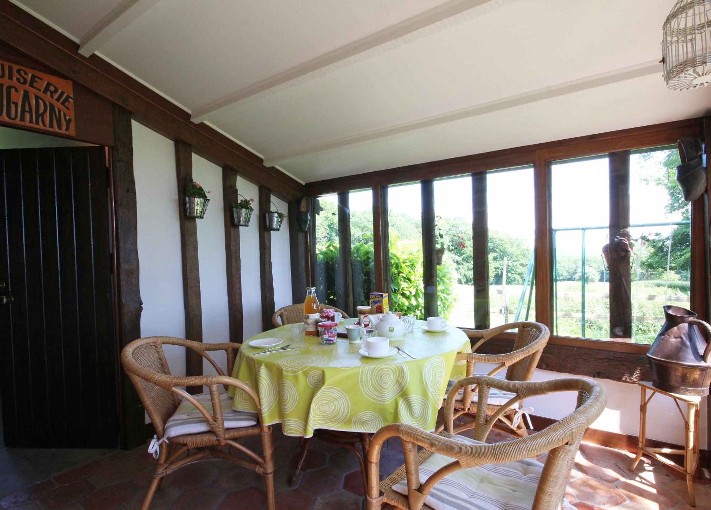 A dining area with wicker chairs and a table set for four, featuring a green tablecloth.
