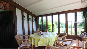 A dining area with wicker chairs and a table set for four, featuring a green tablecloth.