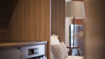 Une chambre d’hôtel avec une armoire en bois, un lit recouvert d’une couette blanche, une lampe et une petite table avec une lampe.