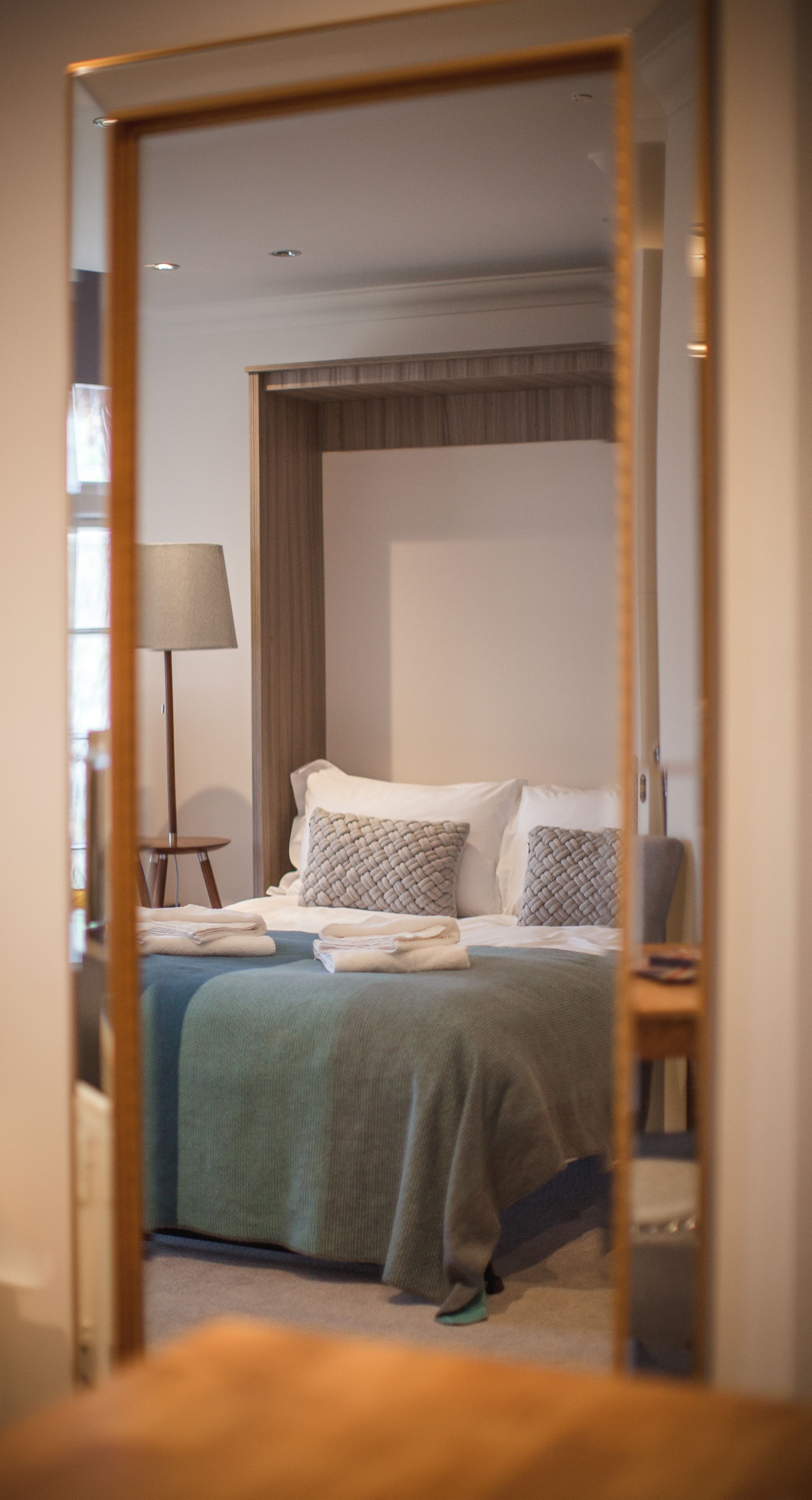 Un dormitorio con cama, almohadas, lámpara y espejo.
