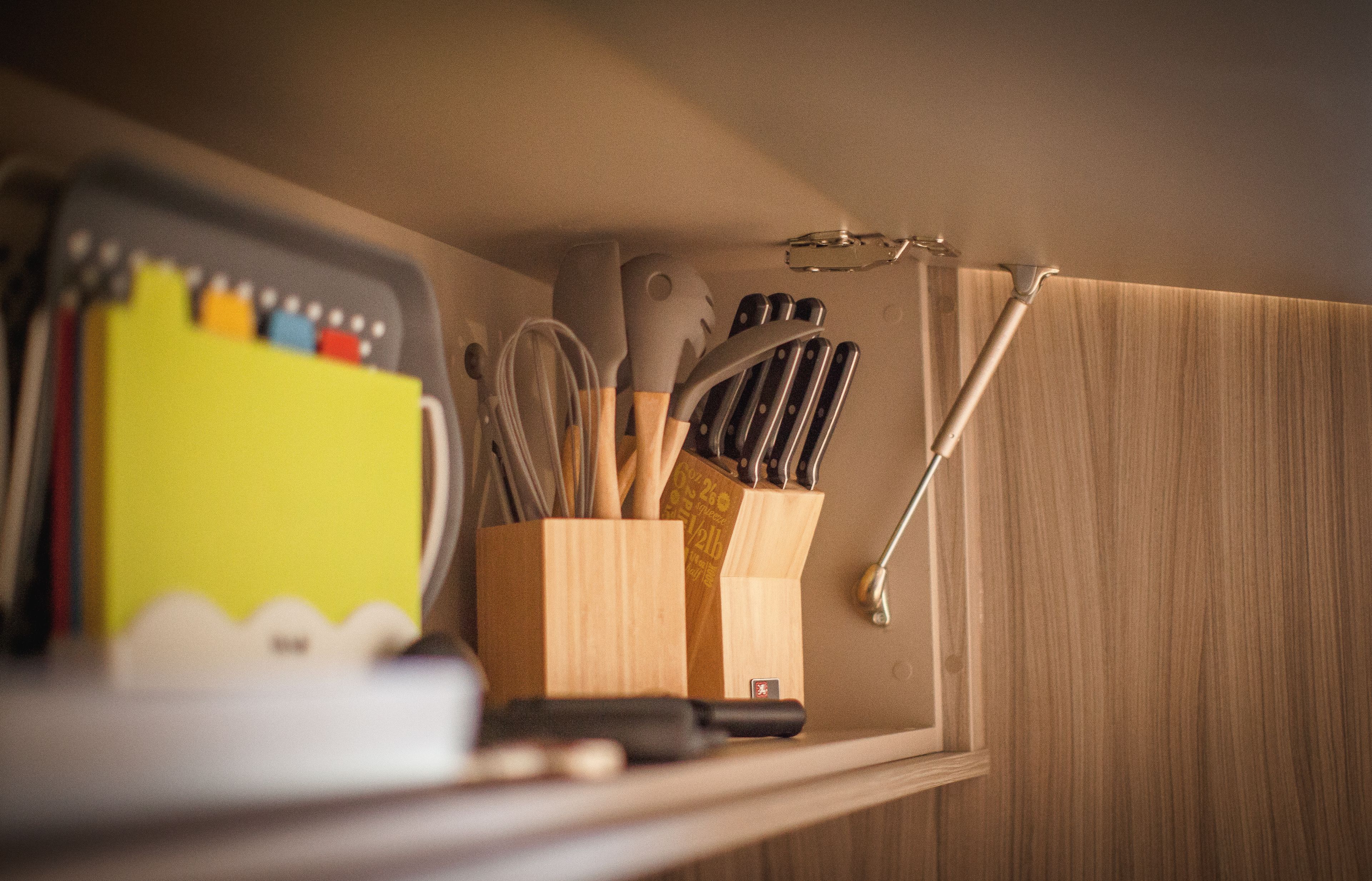 A kitchen with wooden cabinets, a yellow appliance, and various utensils.