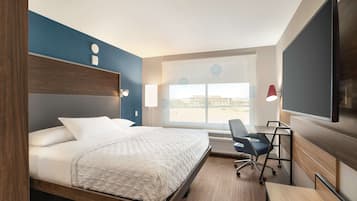 Ein Hotelzimmer mit Bett, Schreibtisch, Stuhl, Fernseher und großem Fenster.