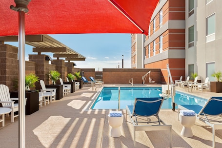 Una piscina al aire libre, sombrillas, sillones reclinables de piscina