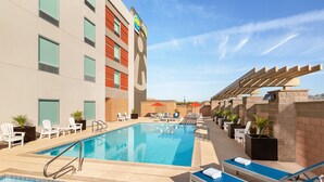 Un espace piscine d’hôtel comprenant plusieurs chaises longues, une petite piscine et un bâtiment avec une enseigne.
