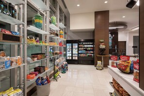A well-organized store with shelves stocked with snacks, a refrigerated section, and a variety of packaged goods.