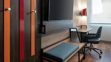 A modern room with a flat-screen TV, a desk, a chair, and a bench.
