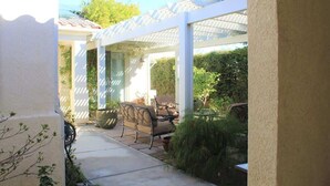 A covered patio with a pergola, outdoor furniture, and a large planter. - Four Seasons Stunner (Palm Springs)