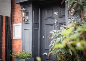 A black door with the number 50, a metal door knocker, and a wall-mounted light fixture. - 50 Bootham Crescent (York)