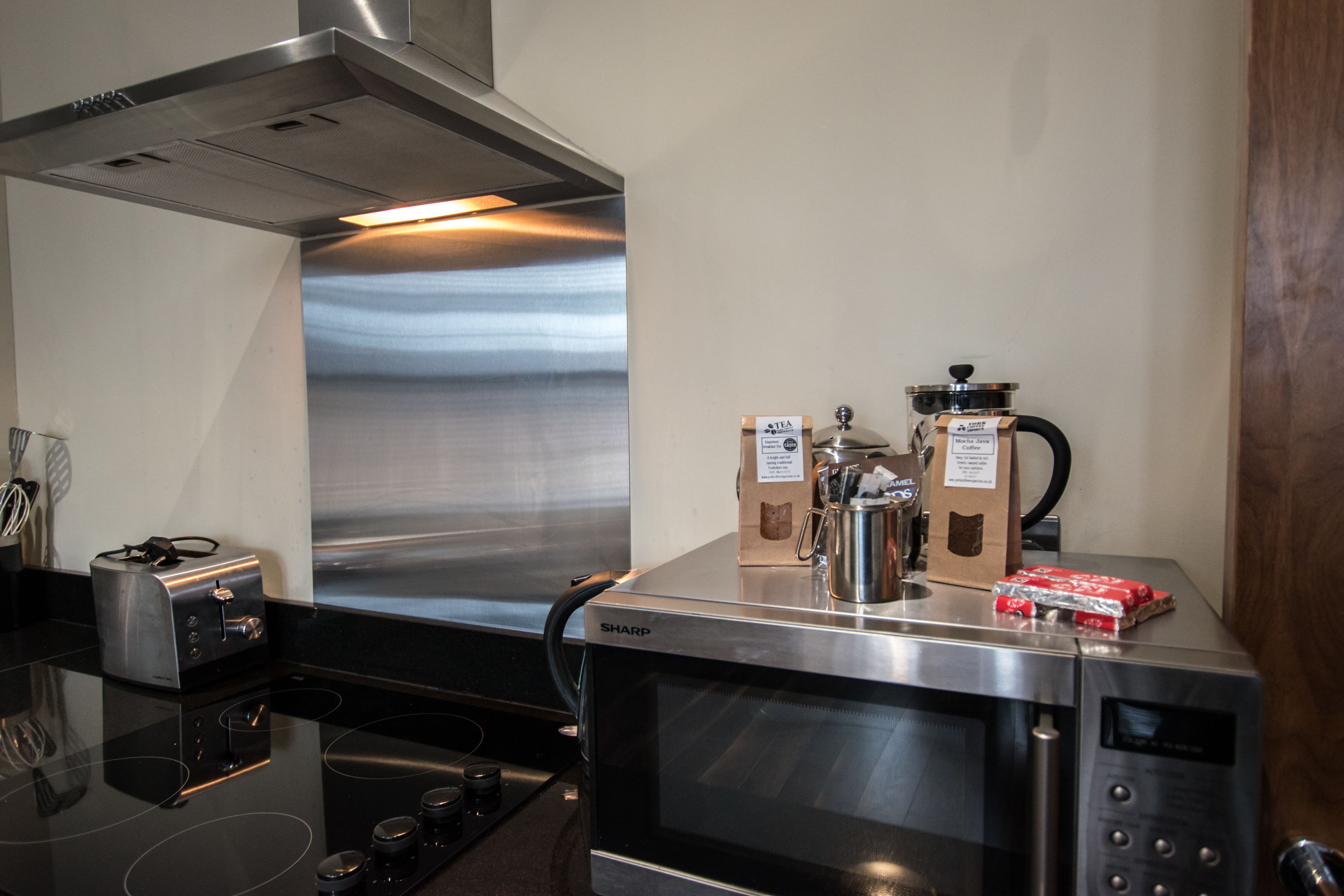 Une cuisine équipée d’une hotte en acier inoxydable, d’un four à micro-ondes, d’un grille-pain et d’une machine à café.