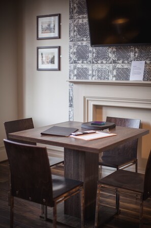 A dining area with a wooden table and chairs, framed pictures on the wall, and a fireplace. - 50 Bootham Crescent (York)