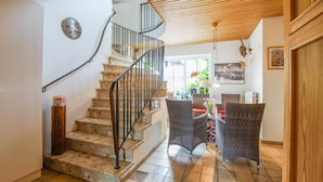 A staircase with a metal railing leading to a dining area with wicker chairs and a table. - Hotel Lindenkrug (Riepsdorf)