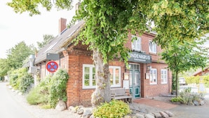A brick building with a sign reading "INDENGROG THOMSDORF". - Hotel Lindenkrug (Riepsdorf)
