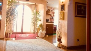 A hotel lobby with a red carpet, large potted plants, a clock, and a framed picture on the wall. - Hotel 2000 Fabriano (Fabriano)