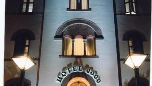 A hotel entrance with a grand archway, a staircase, and two lamps on either side. - Hotel 2000 Fabriano (Fabriano)