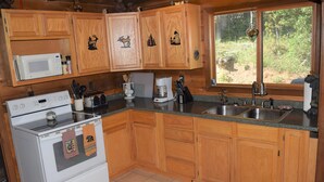A kitchen with wooden cabinets, a microwave, a stove, a coffee maker, and a sink. - Breath Taking Views-Near Yellowstone New Hot Tub.  Just off Union Pass! (Dubois)