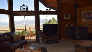 A cozy living room with a leather couch, a television, a fireplace, and a bookshelf. - Breath Taking Views-Near Yellowstone New Hot Tub.  Just off Union Pass! (Dubois)