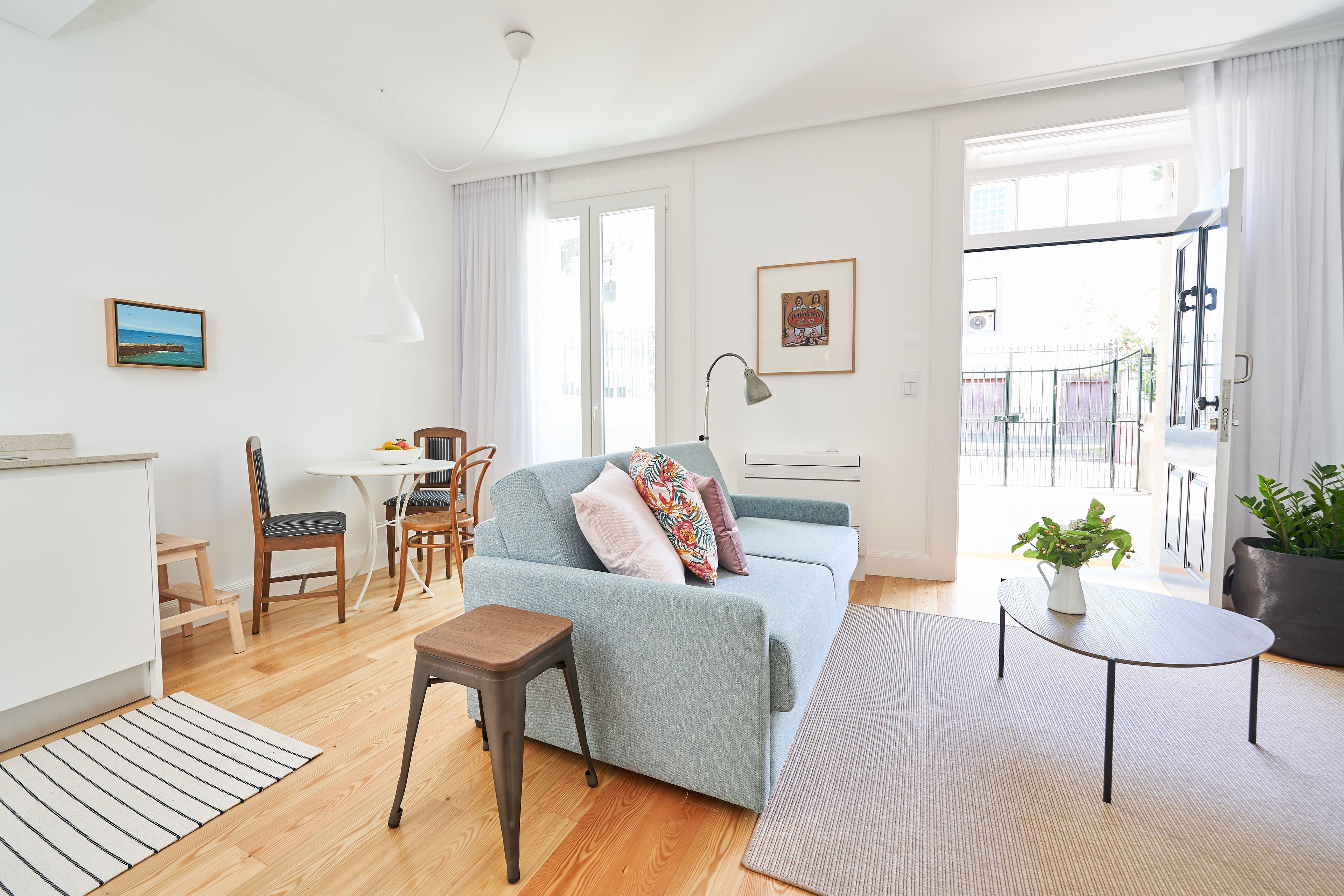 Un salon moderne comprenant un canapé, une table à manger, des chaises, une petite table d’appoint et une plante en pot.