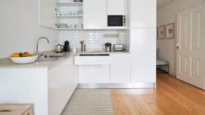 A modern kitchen with white cabinetry, a stainless steel sink, a microwave, and a toaster. - Good Memories Lodge (Funchal)