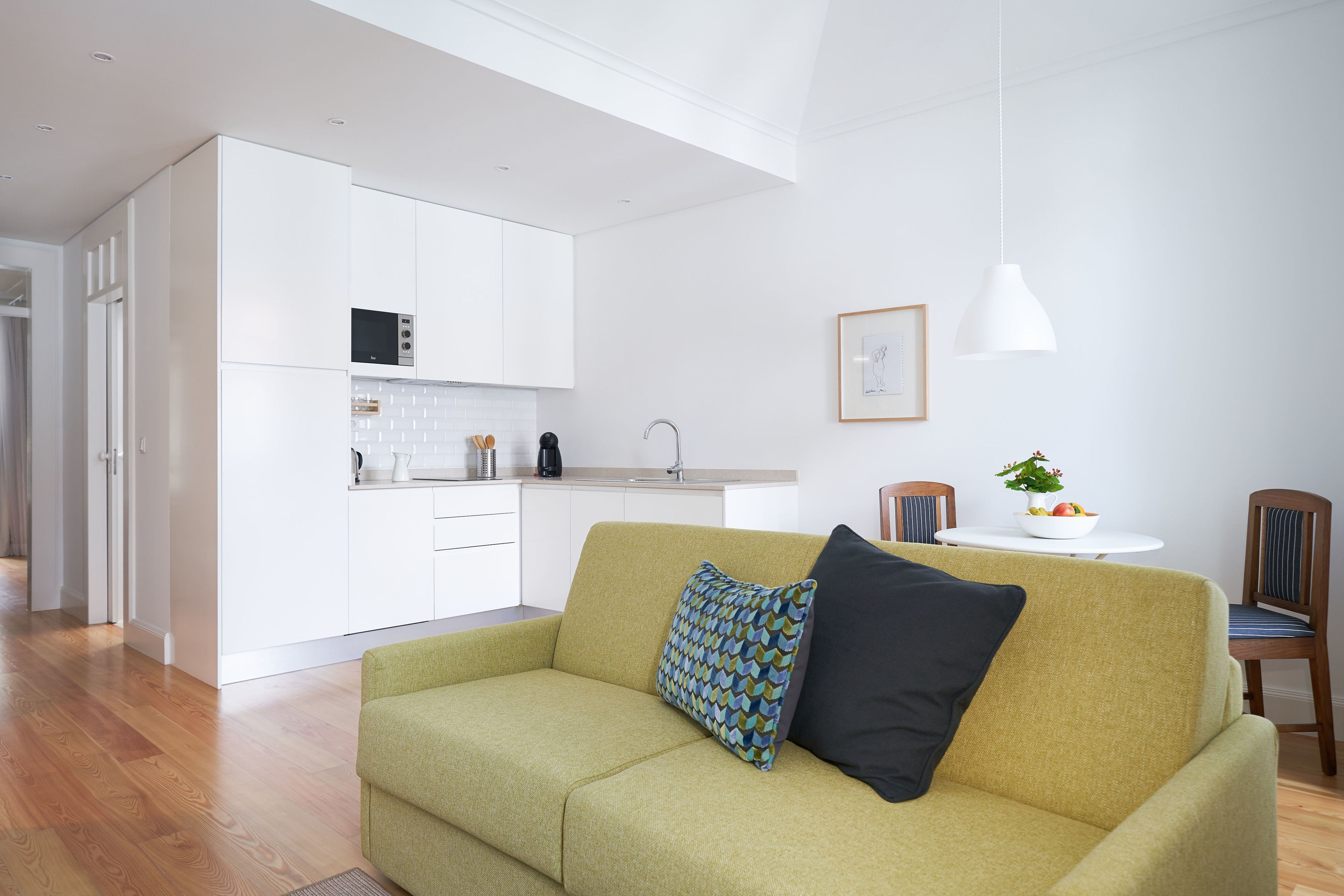 Un salon moderne avec un canapé, une table à manger et des chaises, et un coin cuisine à l’arrière-plan.
