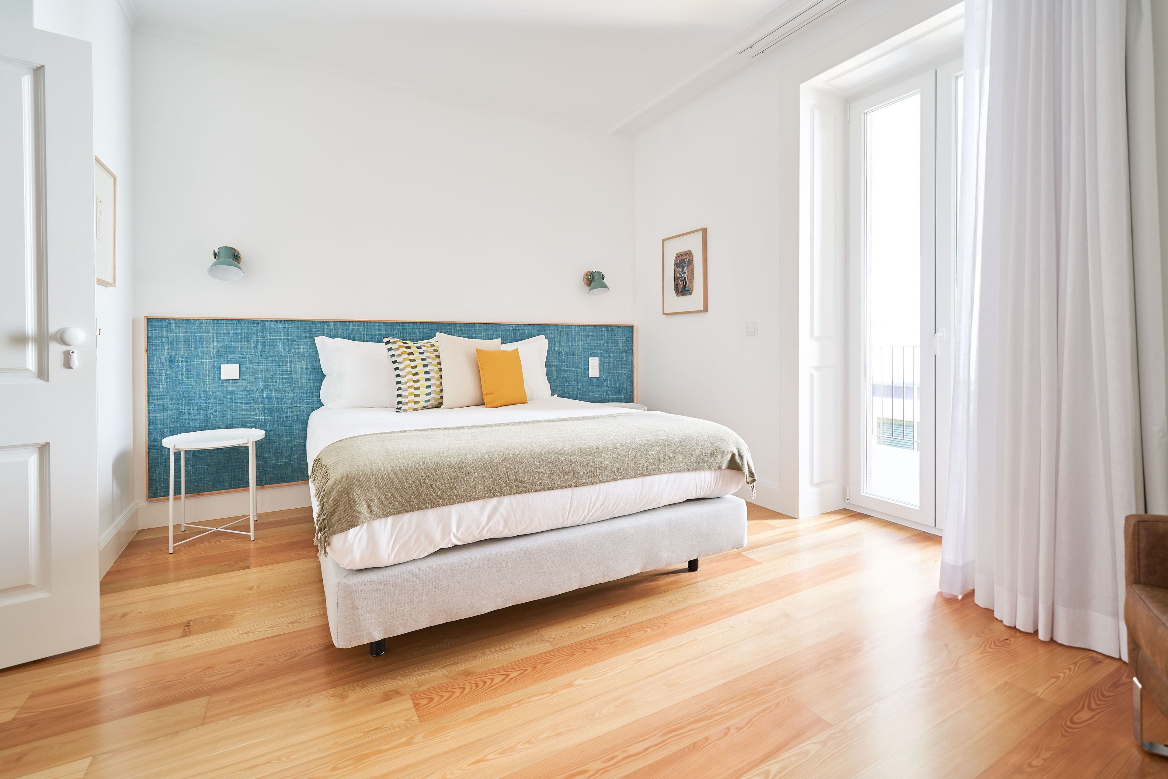 Ein Schlafzimmer mit einem Bett, einem kleinen weißen Tisch und einem Fenster mit Vorhängen.