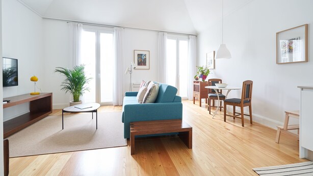 A modern living room with a sofa, coffee table, and dining area. - Good Memories Lodge (Funchal)
