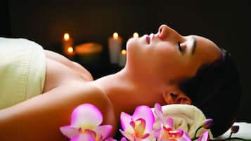 A person lying down with a towel and flowers, suggesting a spa setting.