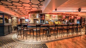 A bar area with a long counter, multiple stools, and a patterned floor. - Bridge House Hotel - Leisure Club & Spa (Tullamore)