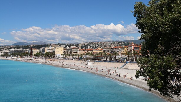 Un paysage urbain côtier avec une vaste plage, des eaux d’un bleu limpide et une variété de bâtiments le long de la côte.