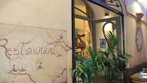 L'intérieur d'un restaurant, avec une fresque murale, des plantes en pot et une table en bois.