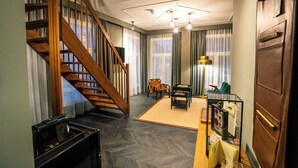 A spacious living area with a wooden staircase, a coffee machine, a sofa, and a glass display case. - The Collector (The Hague)