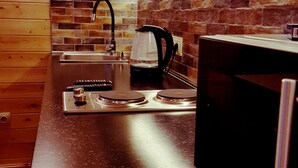 A kitchen with a black countertop, a kettle, a coffee maker, and a brick backsplash. - Beautiful and cozy studio style apartment (Gudauri)